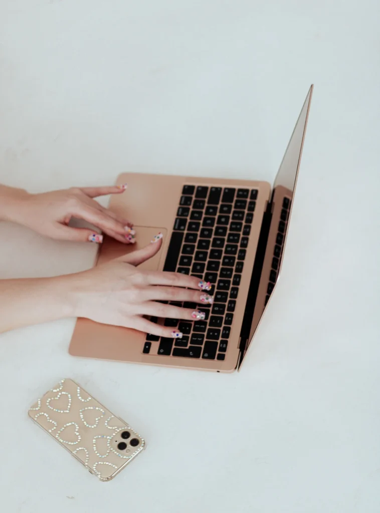 Zbliżenie na dłonie piszące na laptopie.