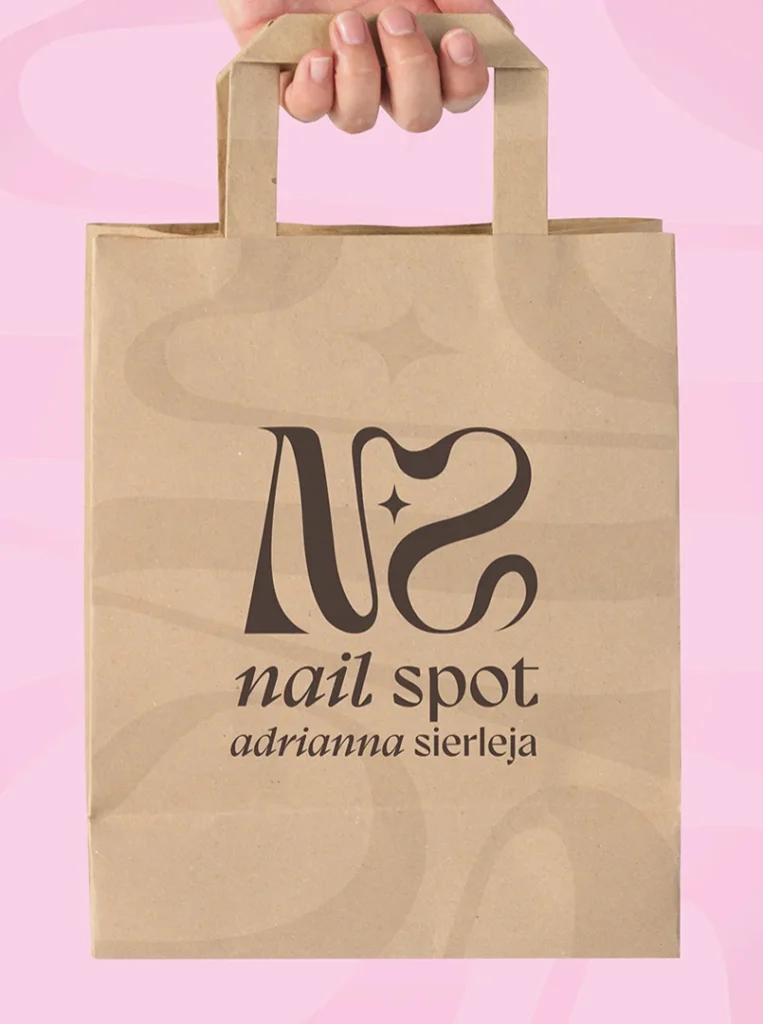 Torba papierowa z logo „Nail Spot” na różowym tle.