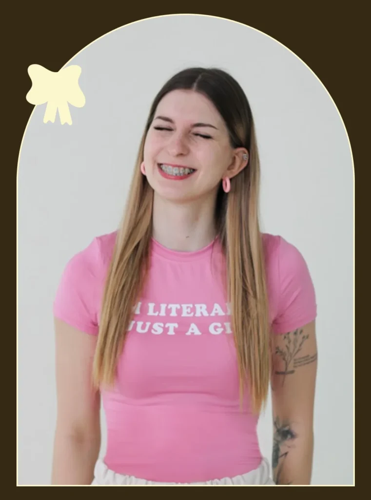 Kobieta w różowej koszulce „Literally just a girl”, uśmiechnięta